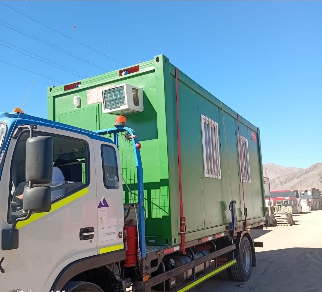 Camión de Transportes Trigo trasladando contenedor oficina verde en faena